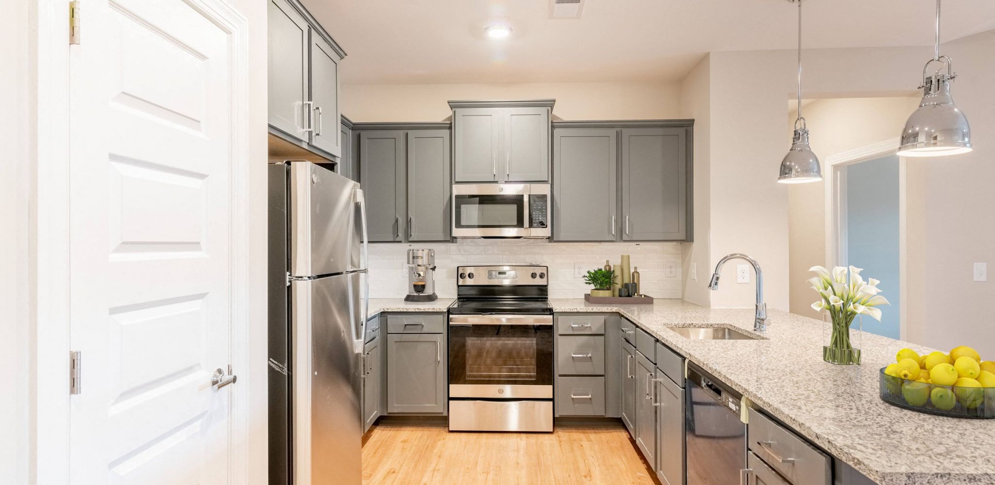 Hawthorne at the Crest apartment kitchen with grey cabinets, stainless steel appliances, and granite countertops