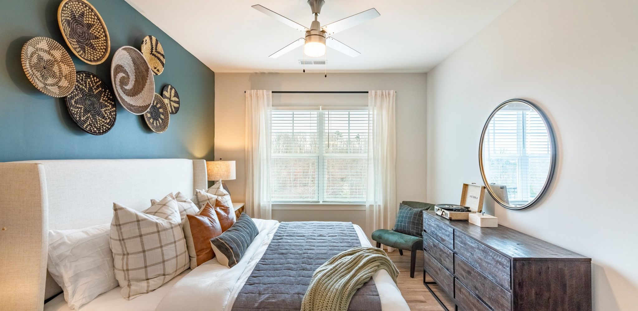 Hawthorne at the Crest apartment bedroom with large mirror, bed, dresser, and chair